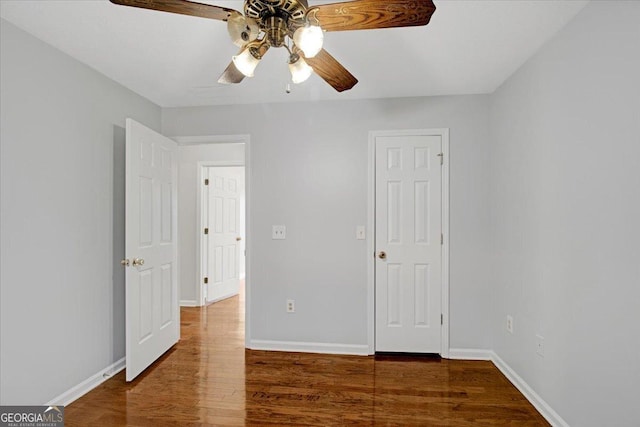 unfurnished bedroom with ceiling fan and dark wood-type flooring