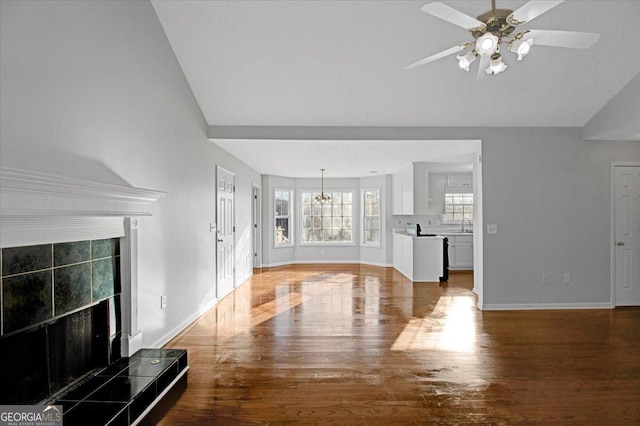 unfurnished living room with vaulted ceiling, sink, ceiling fan with notable chandelier, and hardwood / wood-style flooring