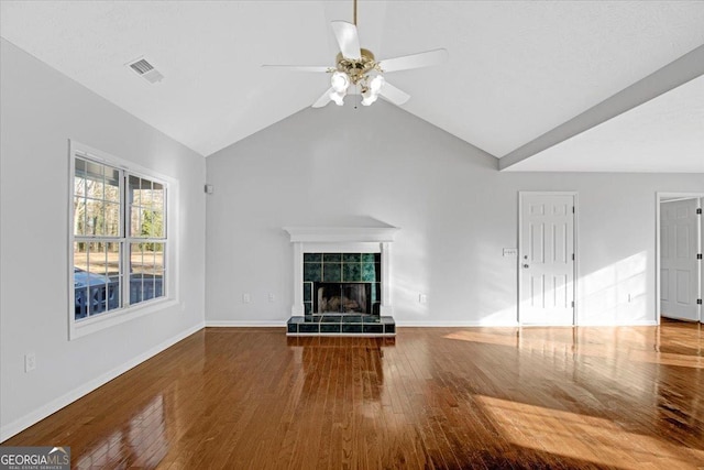 unfurnished living room with ceiling fan, lofted ceiling, wood-type flooring, and a tile fireplace