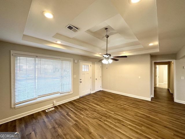 interior space with a raised ceiling, ceiling fan, and dark hardwood / wood-style floors