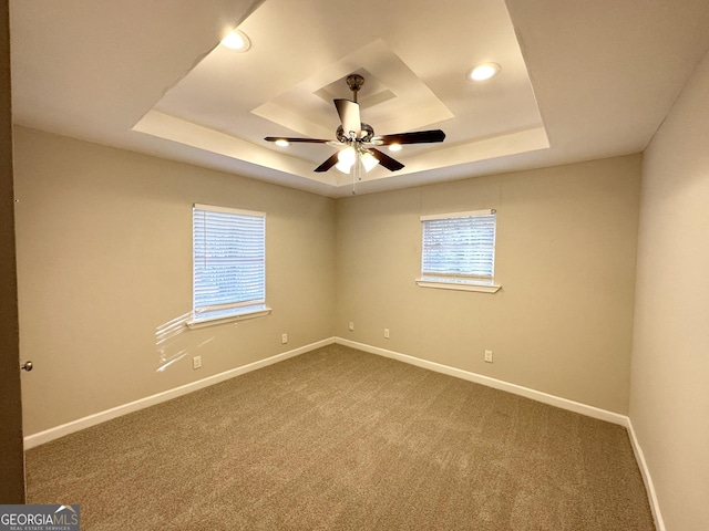 empty room featuring ceiling fan, a raised ceiling, and carpet flooring