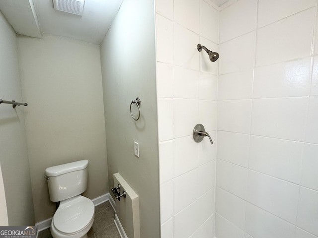 bathroom with a tile shower and toilet