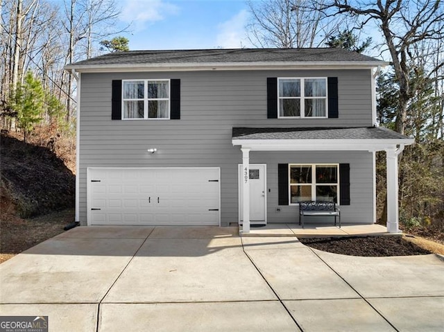 traditional home with covered porch, an attached garage, and concrete driveway