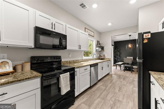 kitchen with black appliances, light wood-type flooring, light stone countertops, sink, and white cabinetry