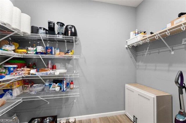 kitchen with light stone counters, light hardwood / wood-style flooring, black appliances, white cabinets, and sink