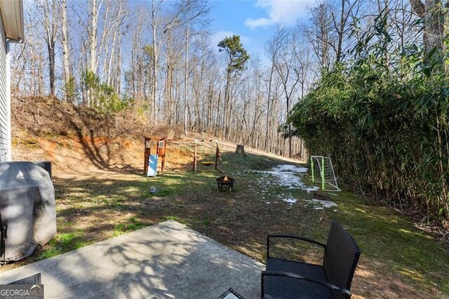 back of property with a fire pit, a playground, and a patio