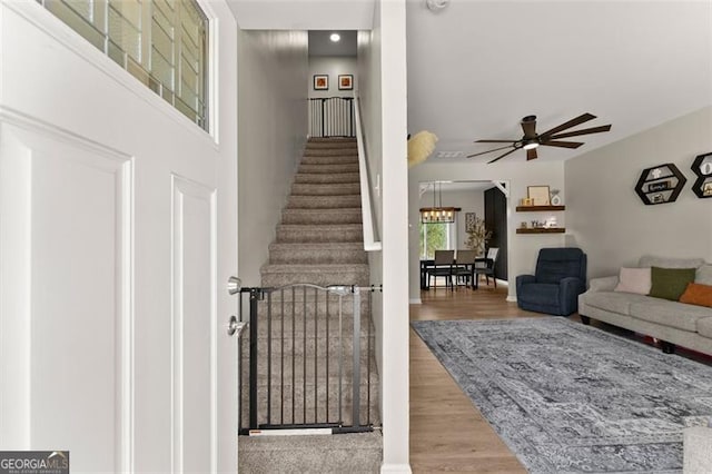 interior space with ceiling fan with notable chandelier, wood finished floors, and stairs