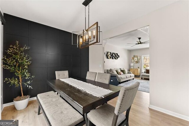 dining area featuring sink, light wood-type flooring, and an inviting chandelier