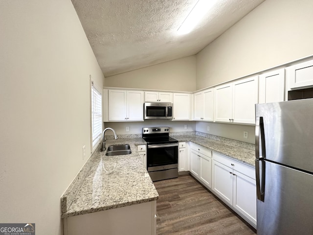 kitchen with light stone counters, a textured ceiling, stainless steel appliances, white cabinets, and sink