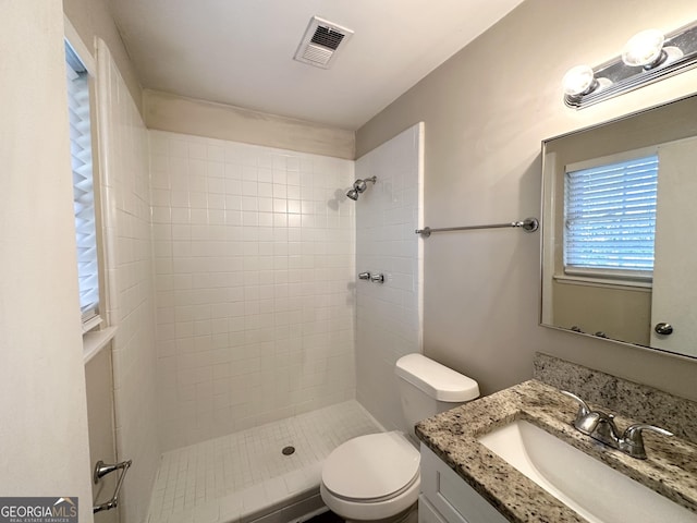 bathroom featuring toilet, a tile shower, and vanity