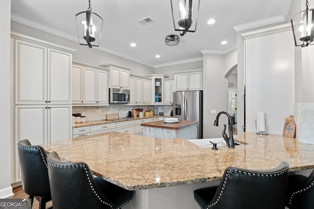 kitchen featuring kitchen peninsula, decorative light fixtures, white cabinetry, appliances with stainless steel finishes, and sink