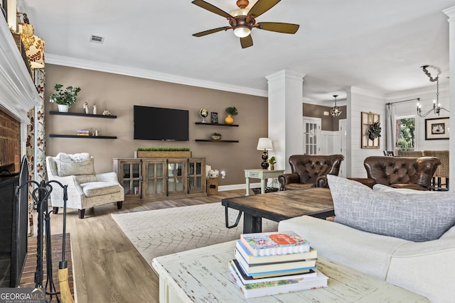 living room featuring ceiling fan with notable chandelier, ornate columns, ornamental molding, and hardwood / wood-style flooring