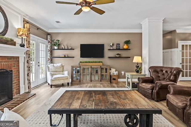 living room with light hardwood / wood-style flooring, french doors, ceiling fan, a fireplace, and ornamental molding