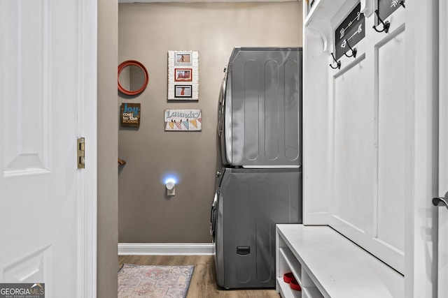washroom with stacked washer / drying machine and light hardwood / wood-style flooring