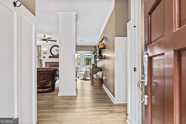 entryway featuring french doors, light wood-type flooring, crown molding, a fireplace, and ceiling fan