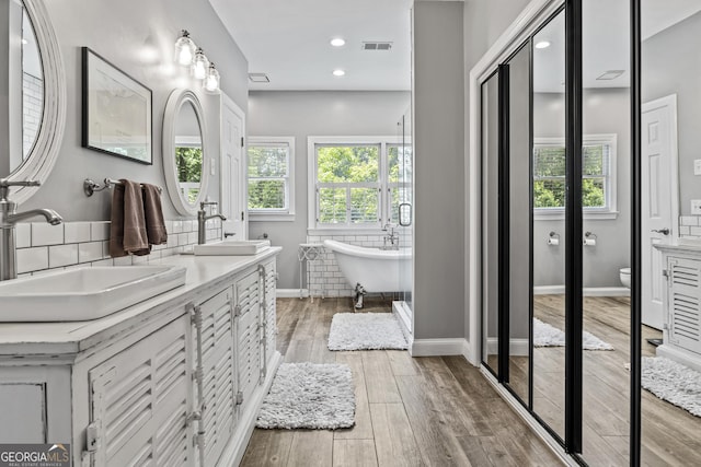 bathroom with toilet, a washtub, vanity, and hardwood / wood-style floors