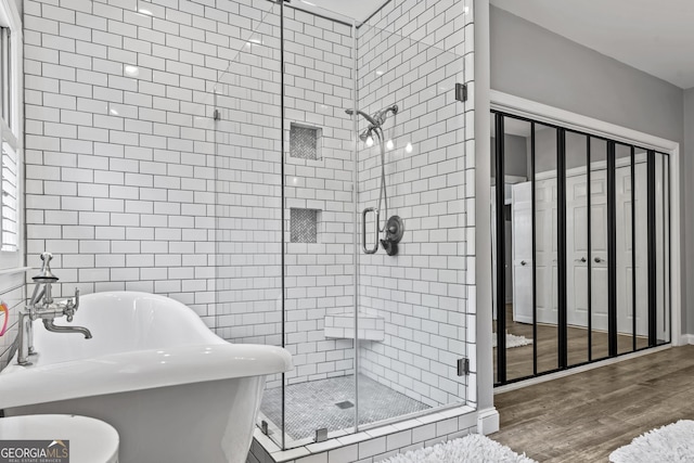 bathroom featuring plus walk in shower and wood-type flooring