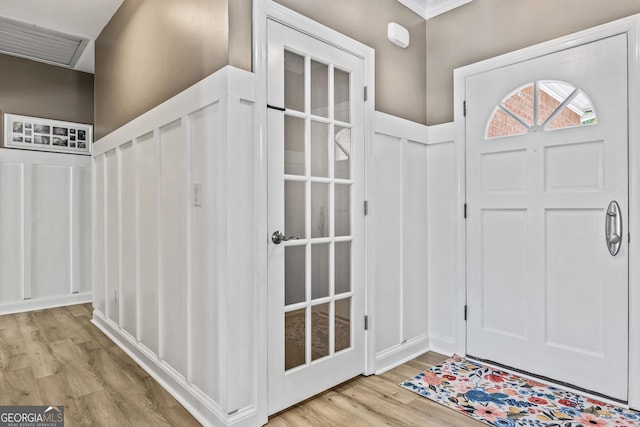 entryway with ornamental molding and light hardwood / wood-style flooring