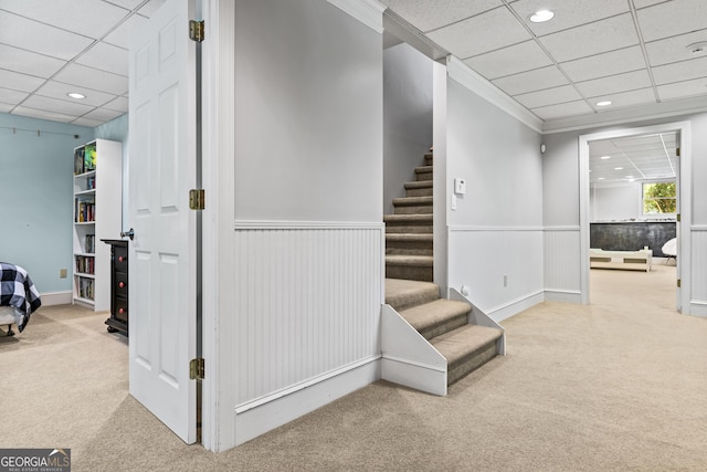 stairs featuring carpet floors, a drop ceiling, and ornamental molding