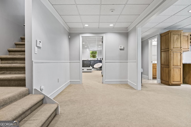 hallway with light colored carpet, a drop ceiling, and ornamental molding