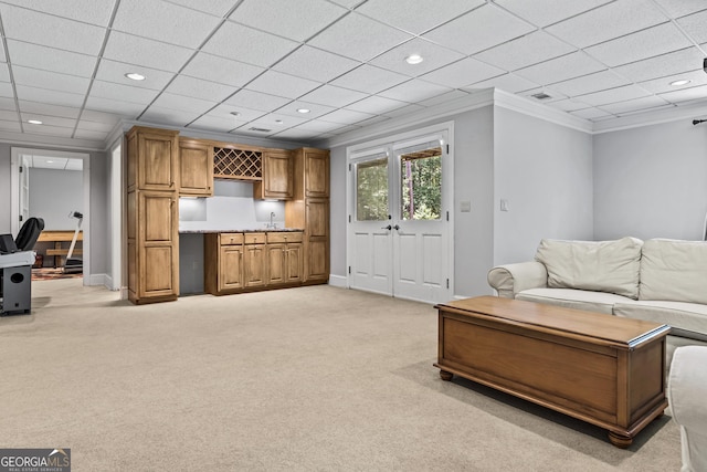 carpeted living room with sink, a paneled ceiling, and crown molding