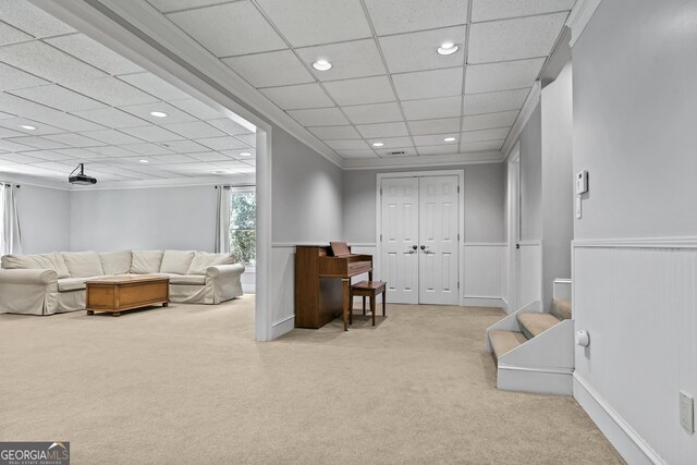 living room featuring ornamental molding, a paneled ceiling, and light carpet