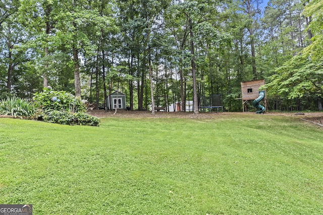 view of yard featuring a playground, a trampoline, and a shed