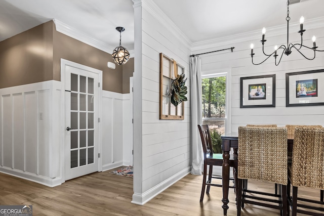 dining room with an inviting chandelier, ornamental molding, and hardwood / wood-style flooring