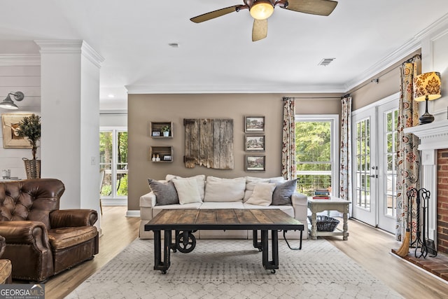 living room featuring a brick fireplace, ceiling fan, light hardwood / wood-style floors, and crown molding