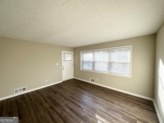 unfurnished room featuring dark wood-type flooring and a textured ceiling