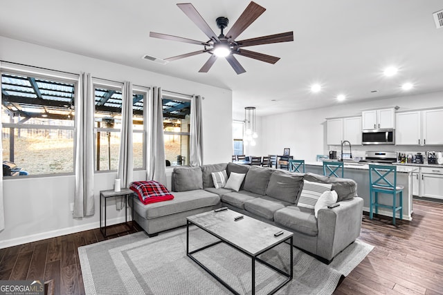 living room with ceiling fan, sink, and dark hardwood / wood-style floors