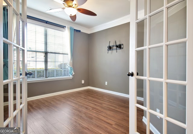 empty room with ornamental molding, a ceiling fan, wood finished floors, french doors, and baseboards