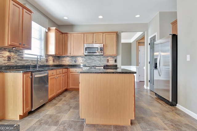 kitchen with dark stone countertops, light brown cabinets, appliances with stainless steel finishes, tasteful backsplash, and a center island