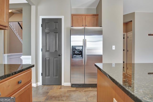 kitchen with dark stone countertops and stainless steel fridge with ice dispenser