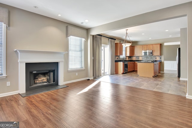 unfurnished living room featuring recessed lighting, light wood-style floors, and a fireplace with raised hearth