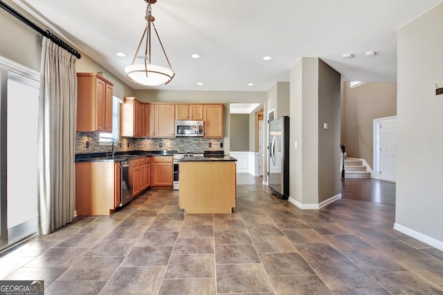 kitchen featuring baseboards, a kitchen island, recessed lighting, stainless steel appliances, and tasteful backsplash