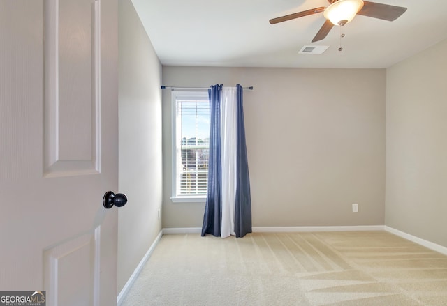 unfurnished room with visible vents, light carpet, baseboards, and a ceiling fan