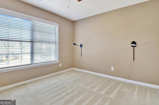 spare room with light carpet, ceiling fan, and baseboards