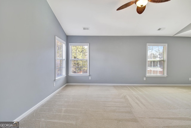 carpeted spare room featuring visible vents, a ceiling fan, baseboards, and vaulted ceiling