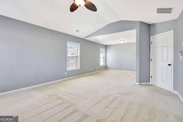 empty room with visible vents, light colored carpet, lofted ceiling, and baseboards