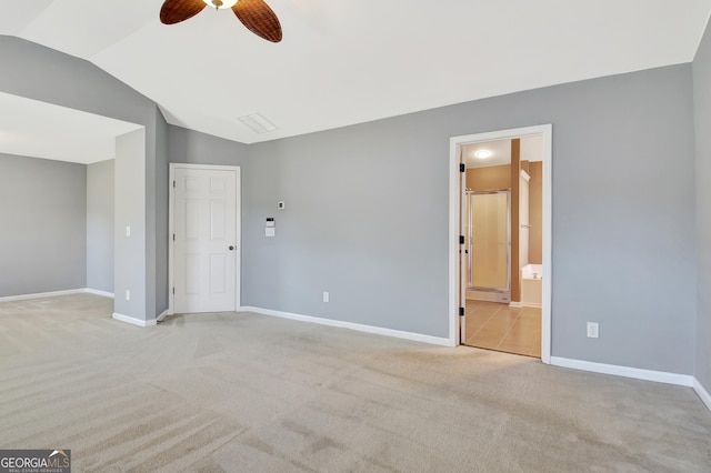 unfurnished bedroom featuring a ceiling fan, baseboards, vaulted ceiling, ensuite bathroom, and light colored carpet