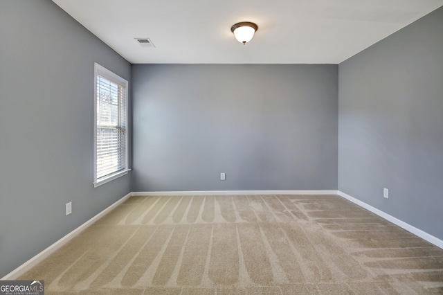 unfurnished room featuring carpet, visible vents, and baseboards