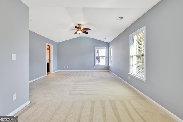 empty room with light carpet, ceiling fan, baseboards, and vaulted ceiling