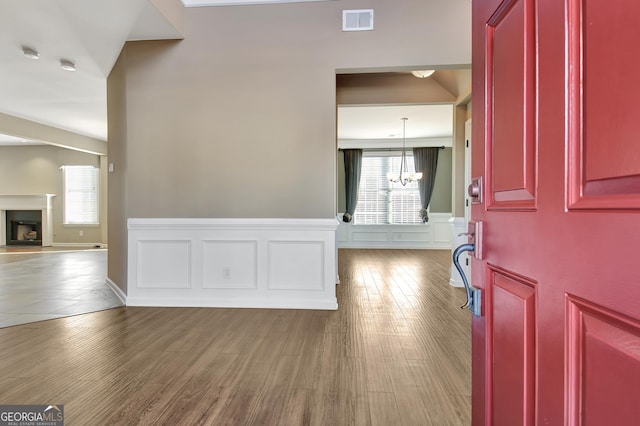 entrance foyer with wood finished floors, visible vents, plenty of natural light, and a fireplace with raised hearth