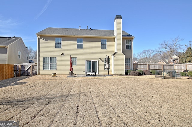 rear view of house featuring a fenced backyard and a chimney