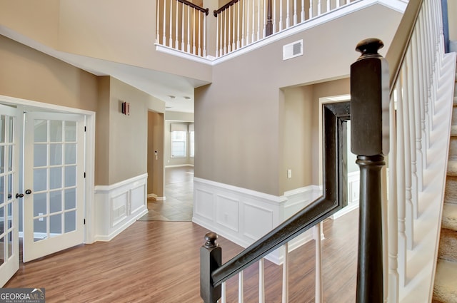 corridor with wood finished floors, stairway, french doors, and visible vents