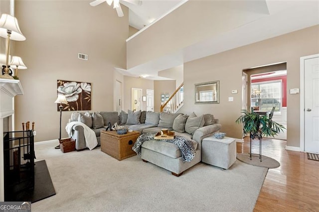 living room featuring a towering ceiling, ceiling fan, and light hardwood / wood-style floors