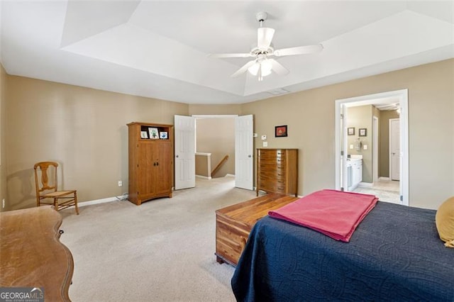 bedroom with ensuite bath, ceiling fan, a tray ceiling, and light carpet