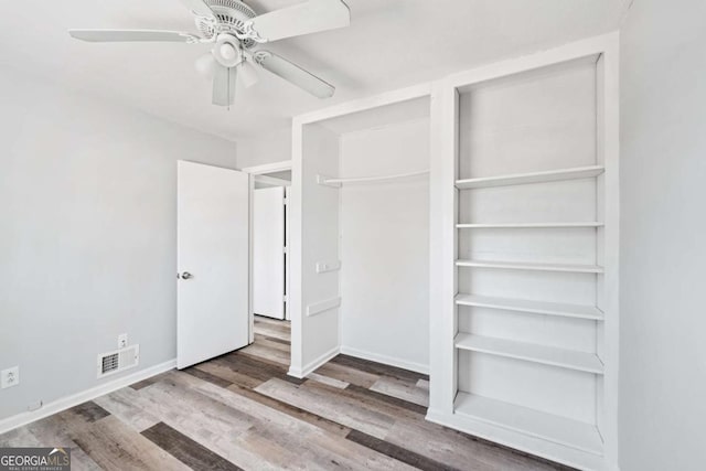 unfurnished bedroom featuring ceiling fan, a closet, and wood-type flooring