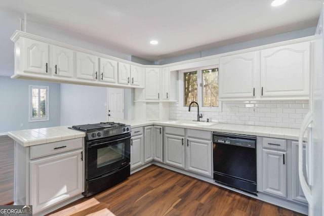 kitchen with sink, white cabinets, kitchen peninsula, black appliances, and dark wood-type flooring